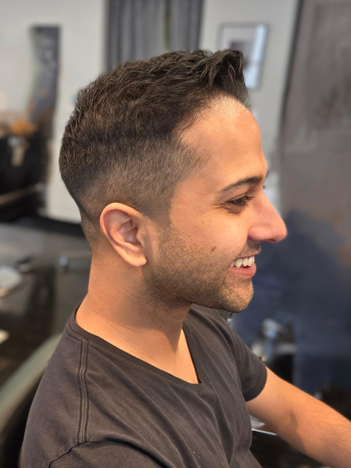 Barber blending a tight fade on the back of a client's head